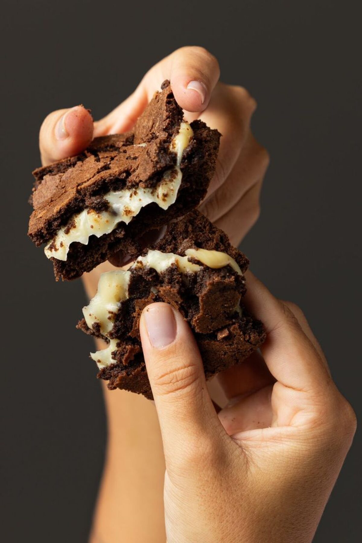 Mãos partindo um brownie ao meio
